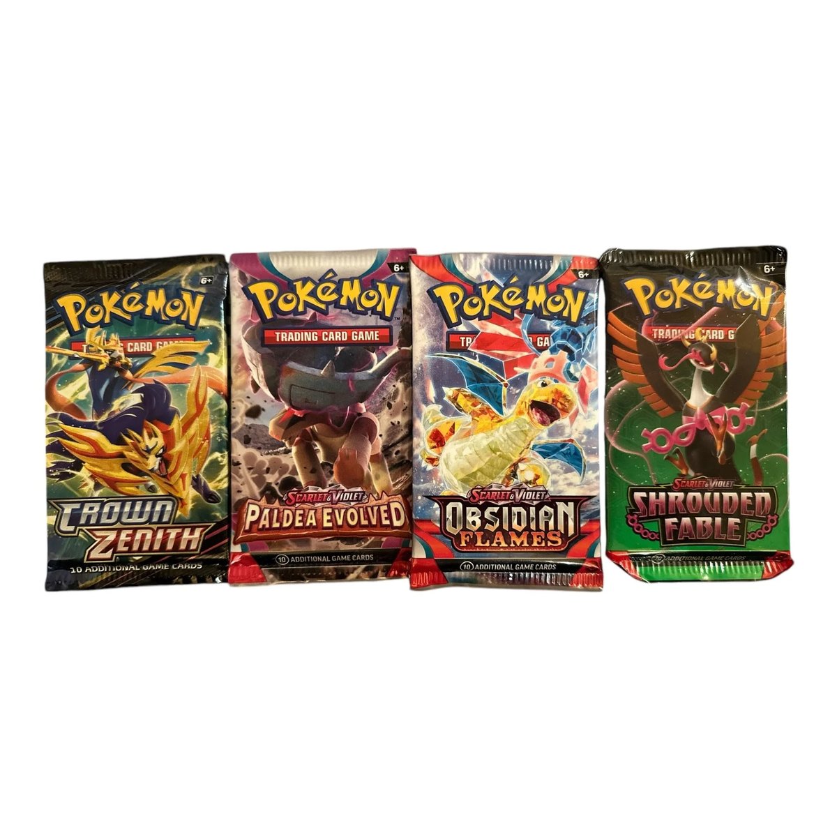 Four Pokémon trading card booster packs arranged side by side.